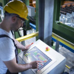 factory worker monitoring industrial machines production remotely control room