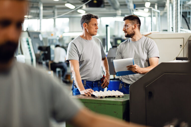 male coworkers communicating while going though paperwork factory