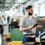 industrial engineer using touchpad while operating cnc machine factory